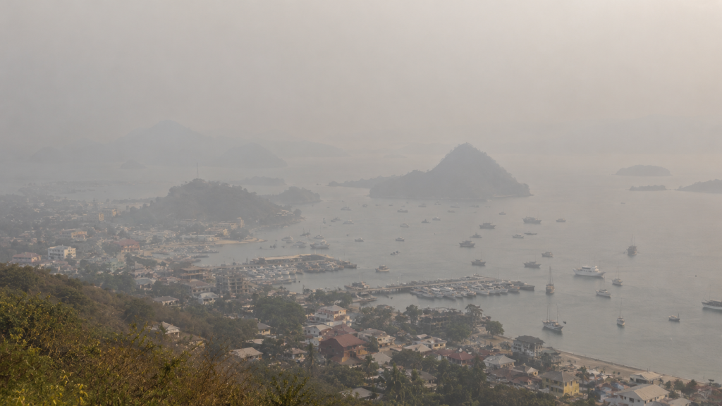 Haze Kembali Selimuti Labuan Bajo, BMKG Catat Jarak Pandang 4 Km 2 Pemandangan kota pesisir Labuan Bajo dari atas bukit yang tampak pudar dan kehilangan kontras akibat selubung partikel haze.